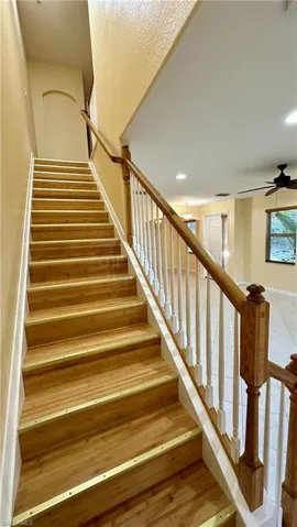 Stairway with hardwood / wood-style flooring, ceiling fan, and recessed lighting