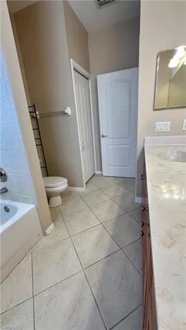 Bathroom featuring vanity, a bath, and light tile patterned floors