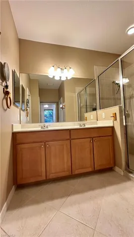 Full bath with double vanity, a stall shower, and a textured ceiling