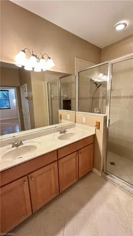 Bathroom with double vanity, a shower stall, and a textured ceiling