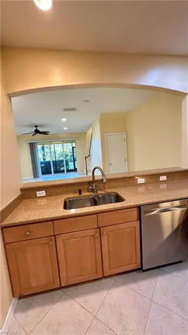 Kitchen with dishwasher, light stone countertops, recessed lighting, brown cabinets, and a ceiling fan