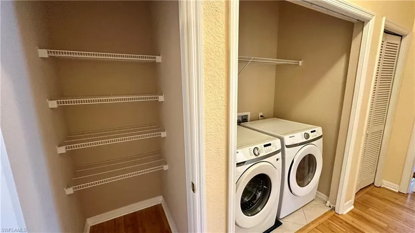 Washroom with independent washer and dryer and light wood-style floors
