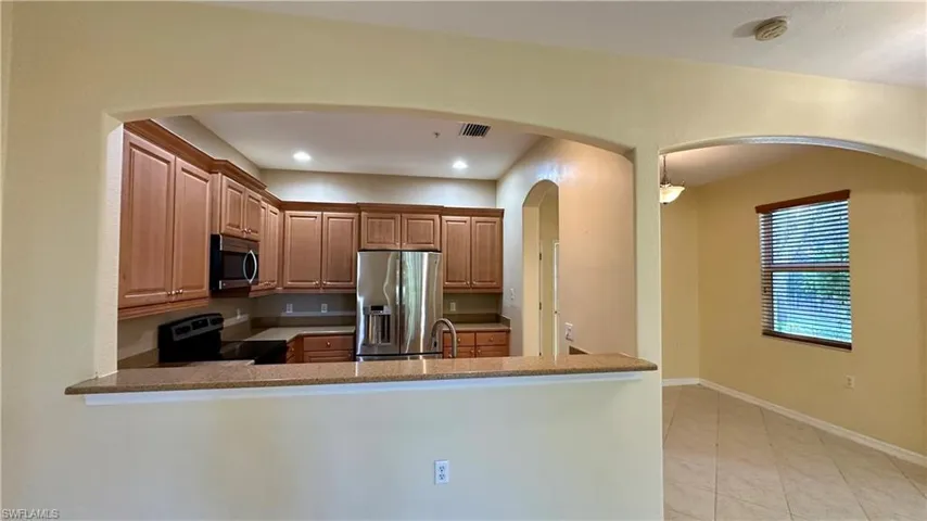 Kitchen with stainless steel appliances, dark stone countertops, recessed lighting, decorative light fixtures, and light tile patterned floors