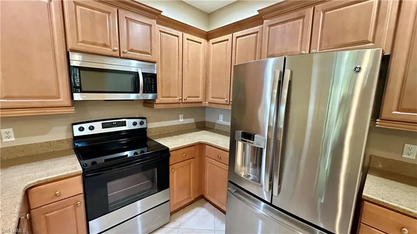 Kitchen featuring appliances with stainless steel finishes, light stone countertops, and light tile patterned floors
