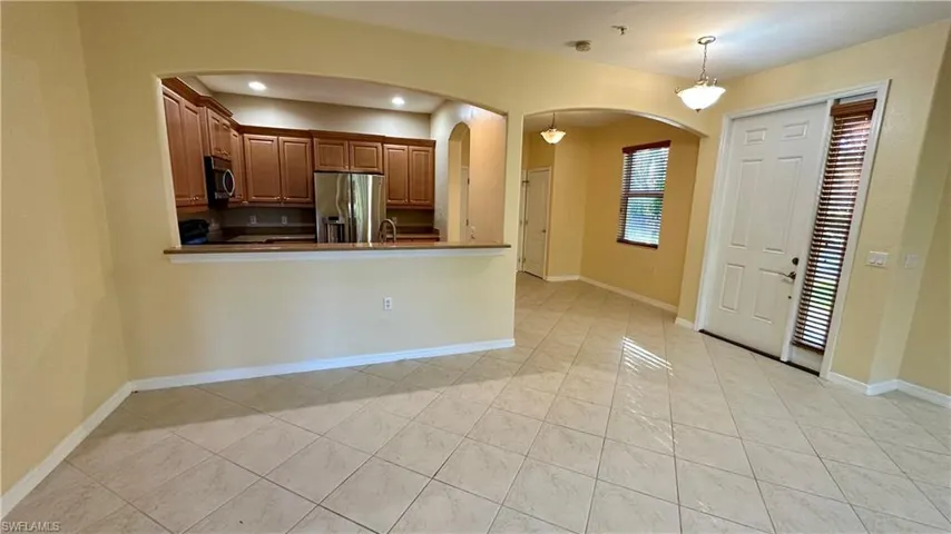 Kitchen with appliances with stainless steel finishes, arched walkways, decorative light fixtures, a peninsula, and dark countertops
