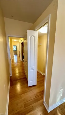 Corridor with light wood-style floors and a textured wall