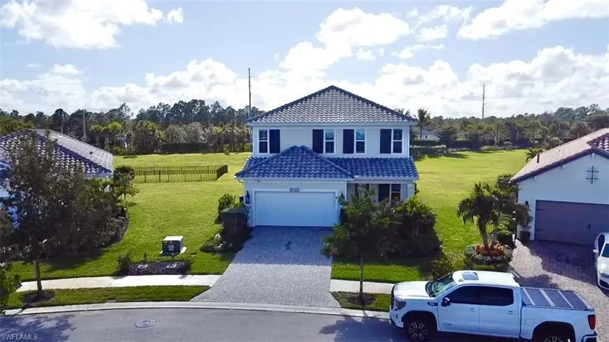 Traditional-style home featuring a tiled roof, decorative driveway, and a garage