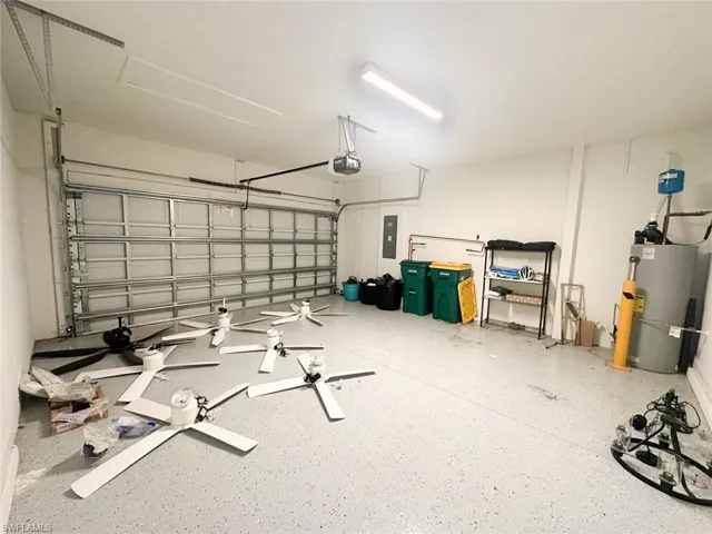 Garage featuring water heater, electric panel, and a garage door opener. Fans do not convey with sale