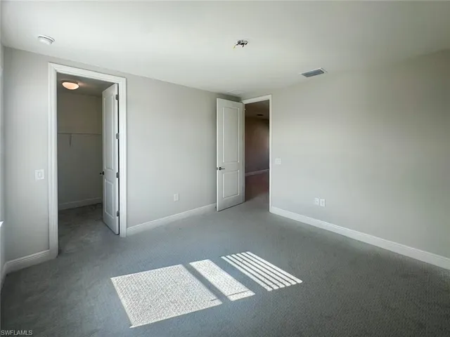 Unfurnished bedroom featuring a walk in closet and carpet flooring