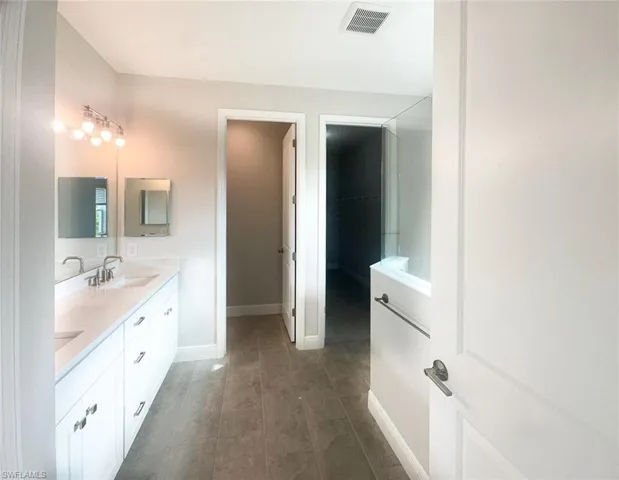 Full bath featuring double vanity and dark wood finished floors