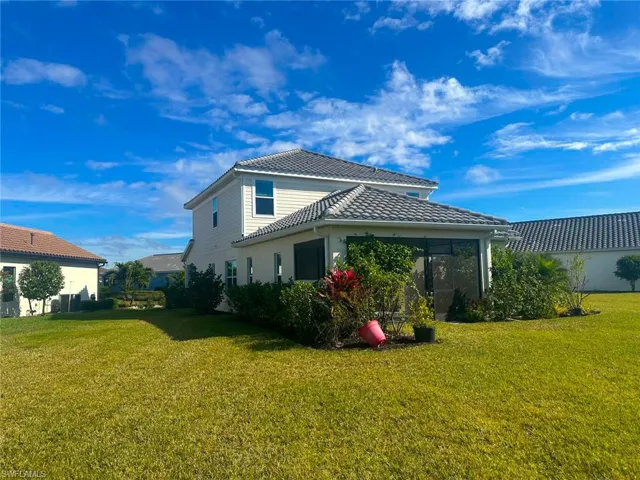 Back of house with a yard, a tile roof, and a sunroom