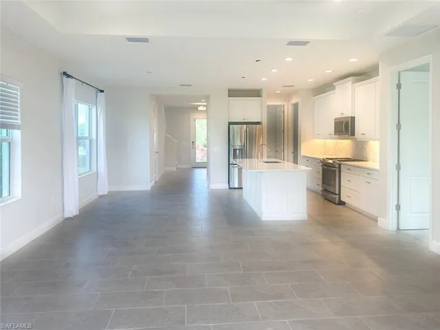 Kitchen featuring white cabinets, appliances with stainless steel finishes, an island with sink, recessed lighting, and tasteful backsplash