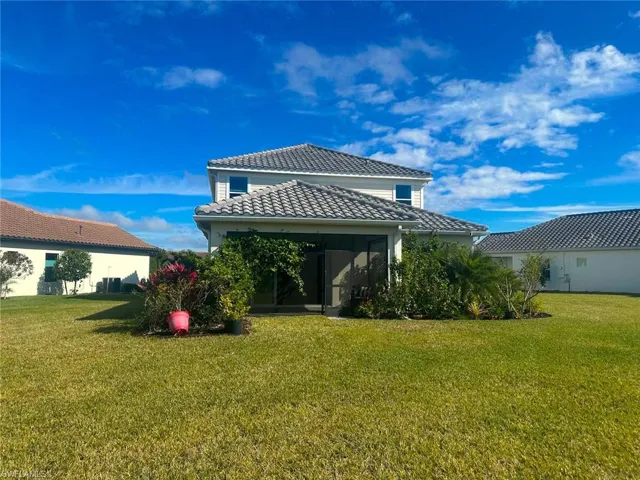 Rear view of house featuring a lawn, a tiled roof, and a sunroom