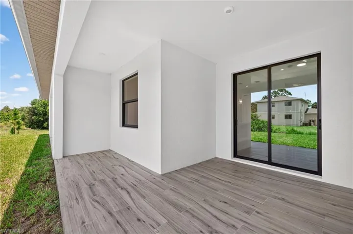 Covered patio featuring wood-finish flooring, white stucco exterior, recessed lighting, and a large sliding glass door