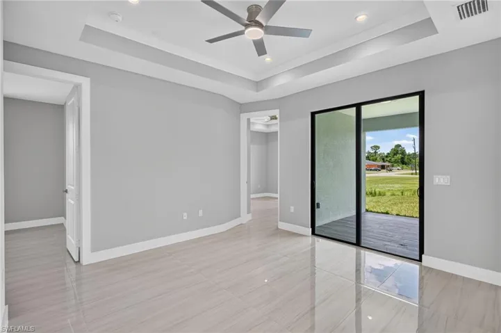 Bright room featuring glossy tile flooring, a tray ceiling with recessed lighting, and a contemporary ceiling fan