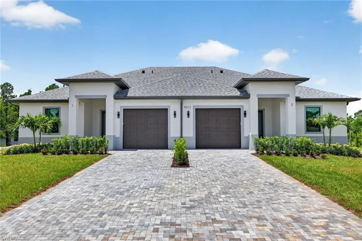Duplex exterior featuring light-colored stucco, a dark shingle roof, and a prominent covered entry