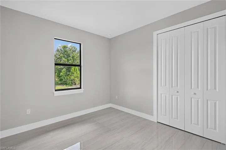 Bright interior space featuring light gray walls, white baseboards, and a window with black trim