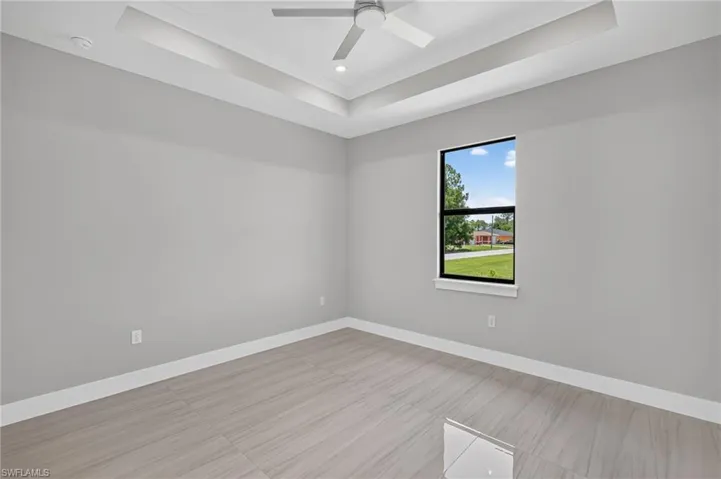 Room featuring tray ceiling with recessed lighting and a ceiling fan