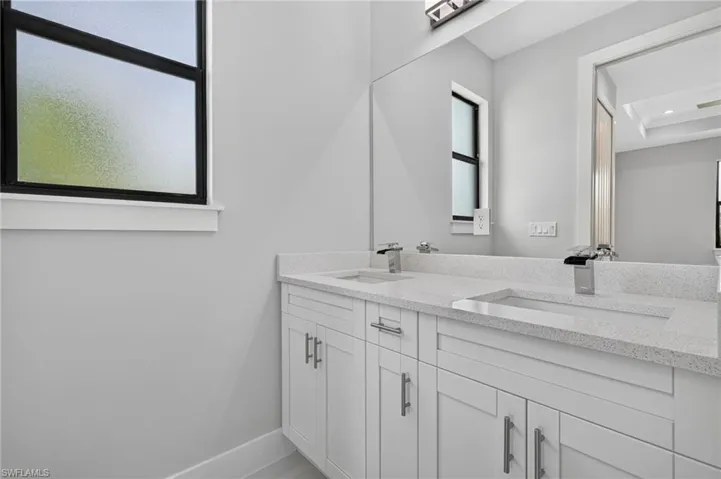 Dual vanity featuring integrated sinks, light-toned countertops, and white cabinetry with brushed nickel hardware