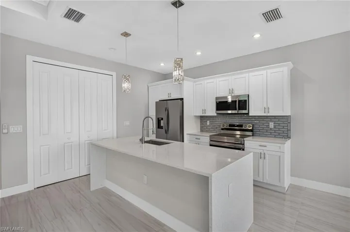 Modern kitchen featuring a waterfall island with a stainless steel sink and a pull-down faucet