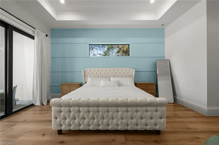 Bedroom featuring access to outside, wood finished floors, a tray ceiling, and recessed lighting