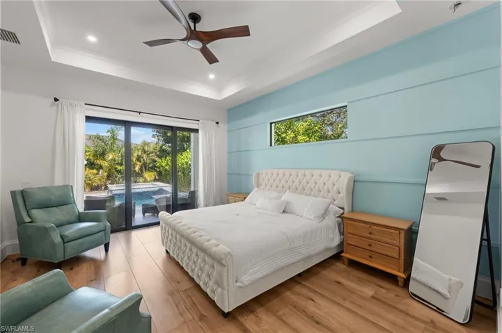 Bedroom featuring access to exterior, wood finished floors, ceiling fan, a raised ceiling, and recessed lighting