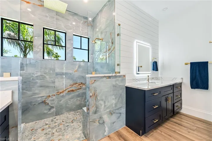Bathroom featuring vanity, a marble finish shower, and light wood-type flooring