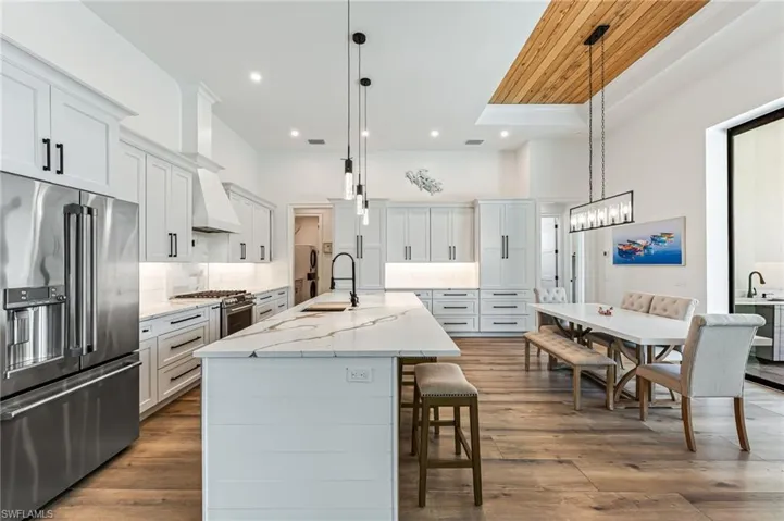 Kitchen with high end appliances, white cabinets, decorative light fixtures, recessed lighting, and wooden ceiling