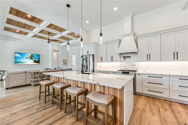Kitchen featuring a wooden ceiling with exposed beams, open floor plan, hanging light fixtures, backsplash, and a breakfast bar area