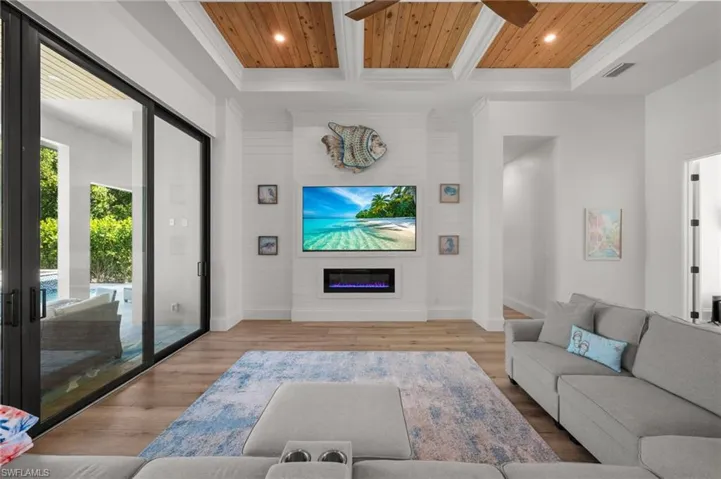 Living area with wooden ceiling, light wood-type flooring, a glass covered fireplace, ceiling fan, and recessed lighting