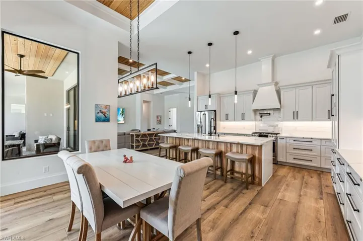 Dining room with light wood-style floors, a chandelier, a ceiling fan, and wooden ceiling