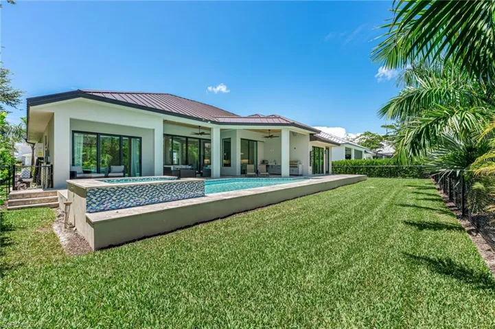 Back of house featuring a ceiling fan, stucco siding, a patio, a fenced backyard, and outdoor lounge area