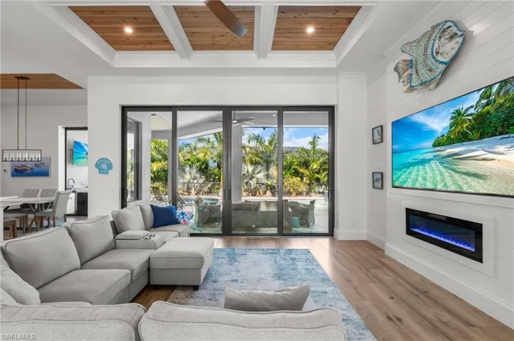 Living area featuring a glass covered fireplace, light wood-style flooring, a high wood beamed ceiling, recessed lighting, and a ceiling fan
