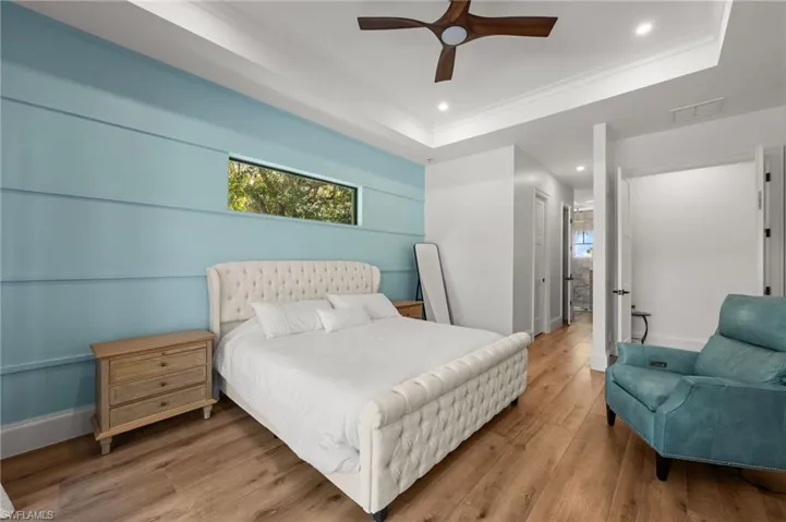 Bedroom with multiple windows, hardwood / wood-style flooring, a tray ceiling, recessed lighting, and a ceiling fan