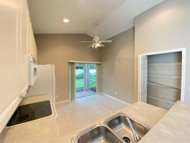 Kitchen featuring high vaulted ceiling, stove, a ceiling fan, light tile patterned floors, and light countertops