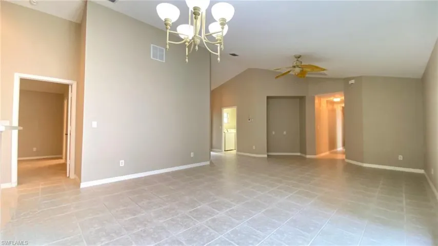 Spare room with a chandelier, ceiling fan, high vaulted ceiling, and light tile patterned flooring