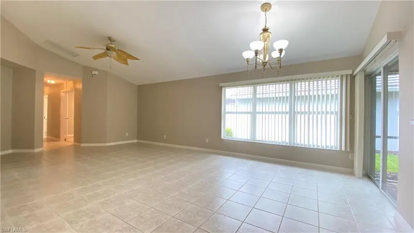 Empty room with lofted ceiling, a ceiling fan, a chandelier, and light tile patterned floors