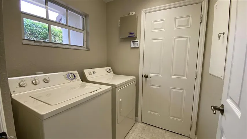 Washroom with washer and dryer and light tile patterned floors