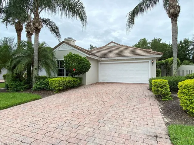 View of front of home featuring decorative driveway, a garage, stucco siding, and a chimney