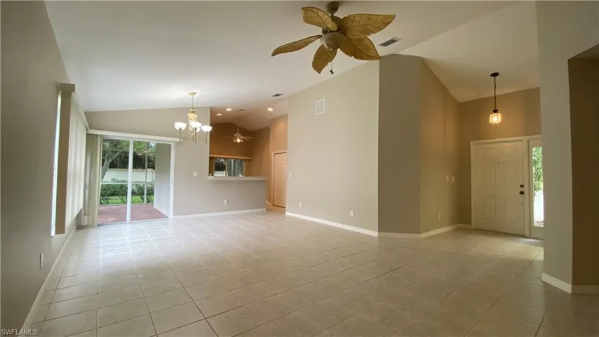 Unfurnished living room featuring a ceiling fan, high vaulted ceiling, light tile patterned flooring, and a chandelier