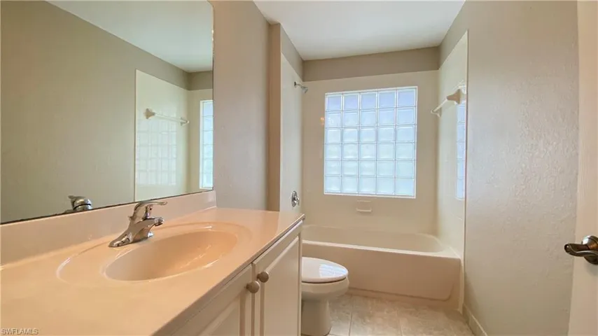 Full bath with bathtub / shower combination, a textured wall, and vanity