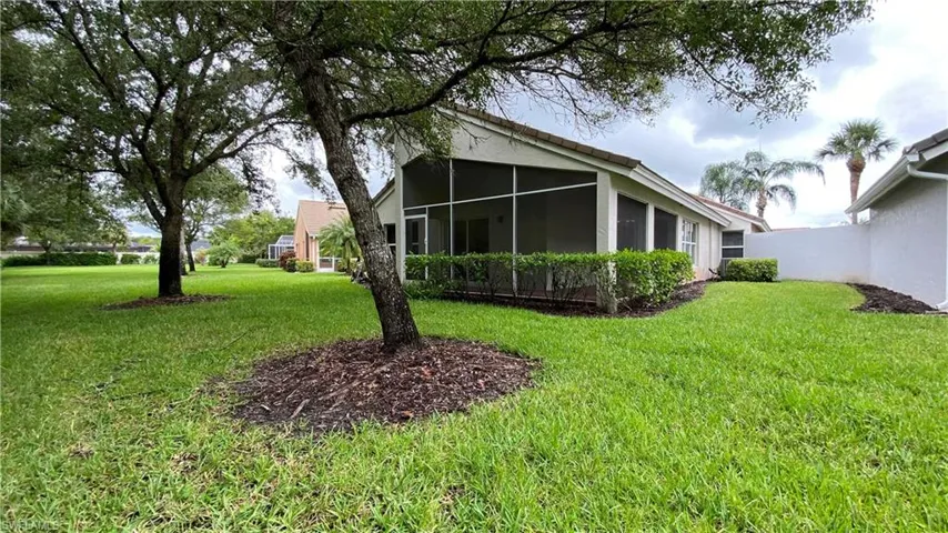 Back of property with stucco siding, a sunroom, and a lawn