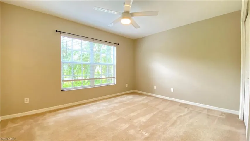 Empty room featuring light colored carpet and ceiling fan