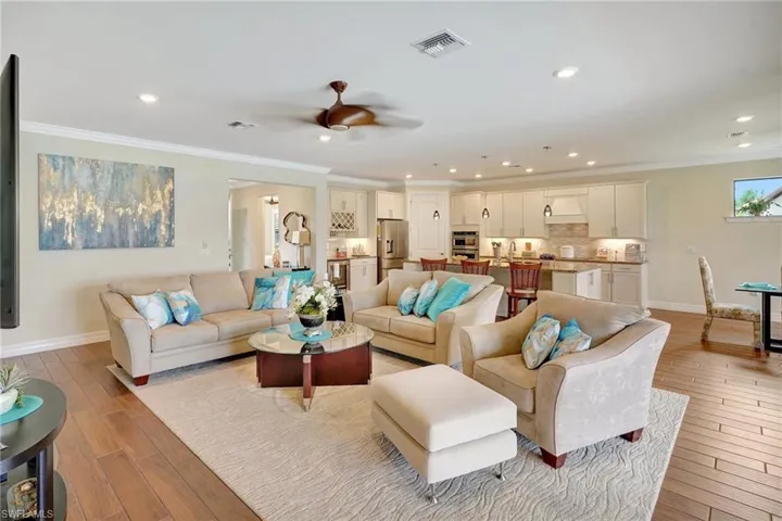 Living area with crown molding, recessed lighting, ceiling fan, and light wood-style flooring