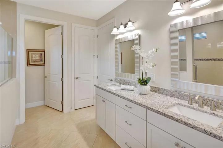 Full bathroom featuring a shower stall, double vanity, and light tile patterned floors