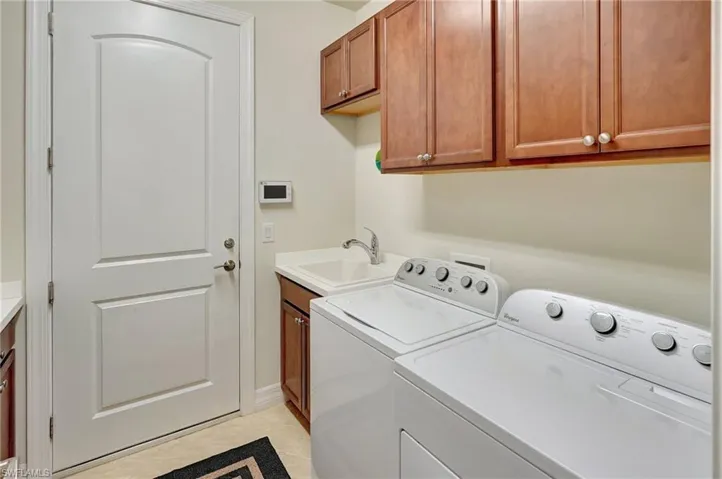 Washroom with cabinet space, separate washer and dryer, and light tile patterned floors
