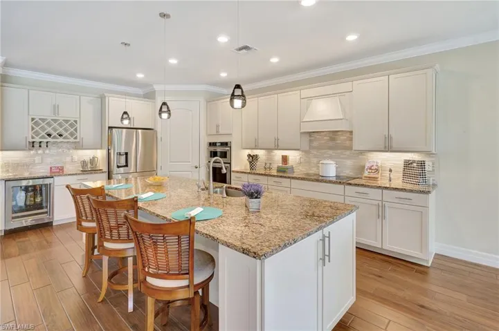 Kitchen featuring crown molding, stainless steel appliances, wine cooler, tasteful backsplash, and pendant lighting