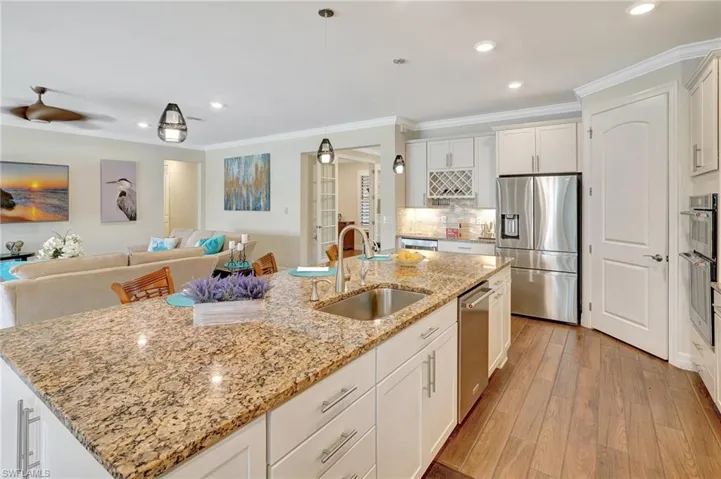 Kitchen featuring stainless steel appliances, crown molding, light stone countertops, white cabinets, and recessed lighting