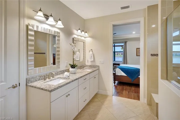 Ensuite bathroom featuring double vanity, a walk in shower, and light tile patterned flooring