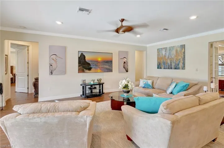 Living area with ornamental molding, a ceiling fan, wood finished floors, and recessed lighting